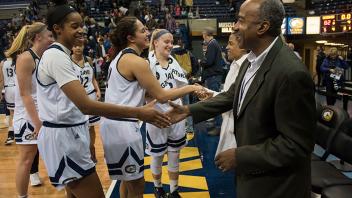 Chancellor May and his wife LeShelle May cheer on the women’s basketball team with a group of student athletes. 