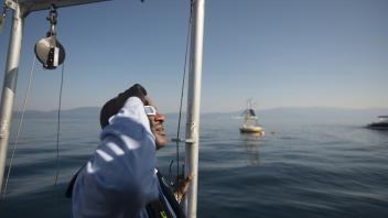 The Chancellor looks up into the sky with special glasses a solar eclipse on a research vessel at Lake Tahoe.