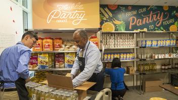 Chancellor May unpacks a box of food to stock the pantry at UC Davis. 