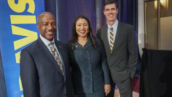 Chancellor May smiles with two Aggie alumni. 