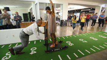 Chancellor Gary May pushes LeShelle May across a green runway on a tackling sled at The ARC (Activiites and Recreation Center).
