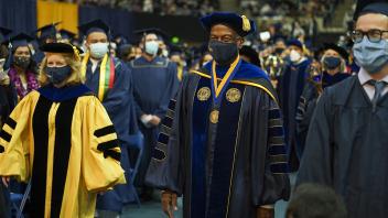 Chancellor May and the provost walk through a crowd at commencement. 
