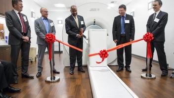 Chancellor Gary May cutting a red ribbon with leaders standing beside him.