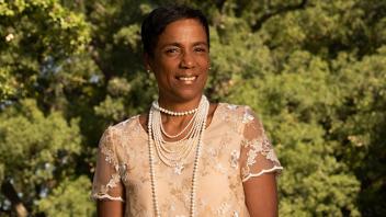 LeShelle May wearing a pink dress and a layered pearl necklace while smiling outdoors at UC Davis