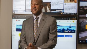 Chancellor Gary May stands in front of a large display screen with information on it