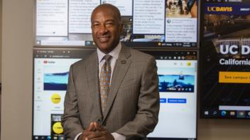 Chancellor Gary May stands in front of a large display screen with information on it