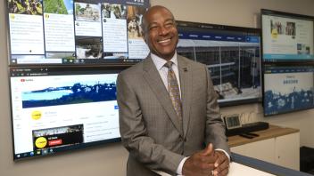 Chancellor Gary May stands in front of a large display screen with information on it