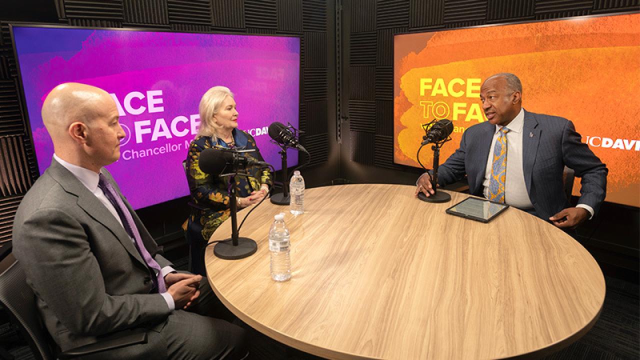 Chancellor May with two other people sitting at table in podcast studio.