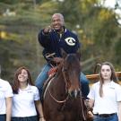 The chancellor rides a horse and points during a holiday celebration at UC Davis. 