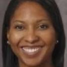 Headshot portrait of a smiling woman with straight dark hair and gray background