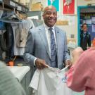 "Chancellor May, in suit and tie, smiles while holding screen-printed T-shirt and being interviewed live for morning TV show"